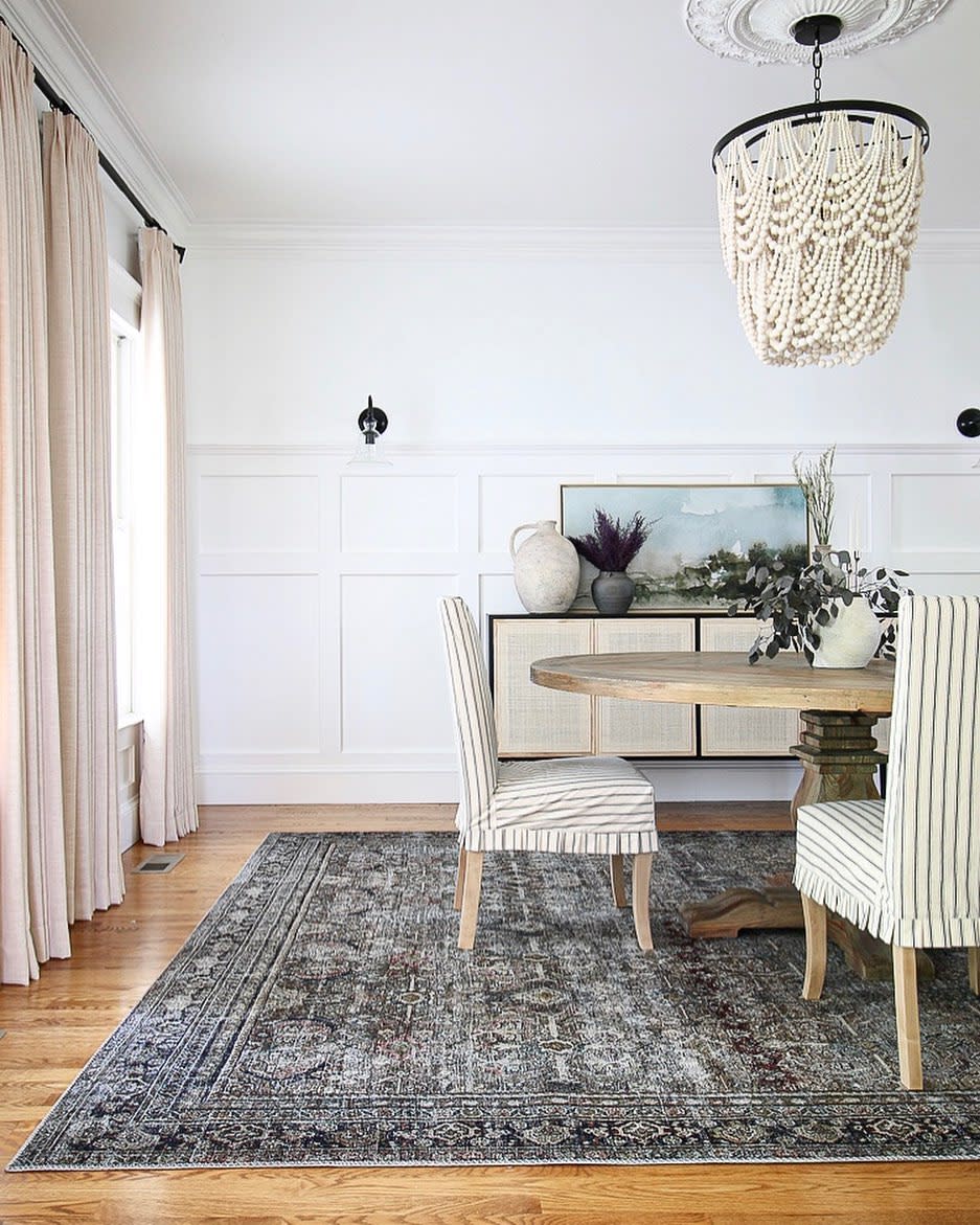 large farmhouse dining room round wood table striped fabric chairs pink curtains floor rug